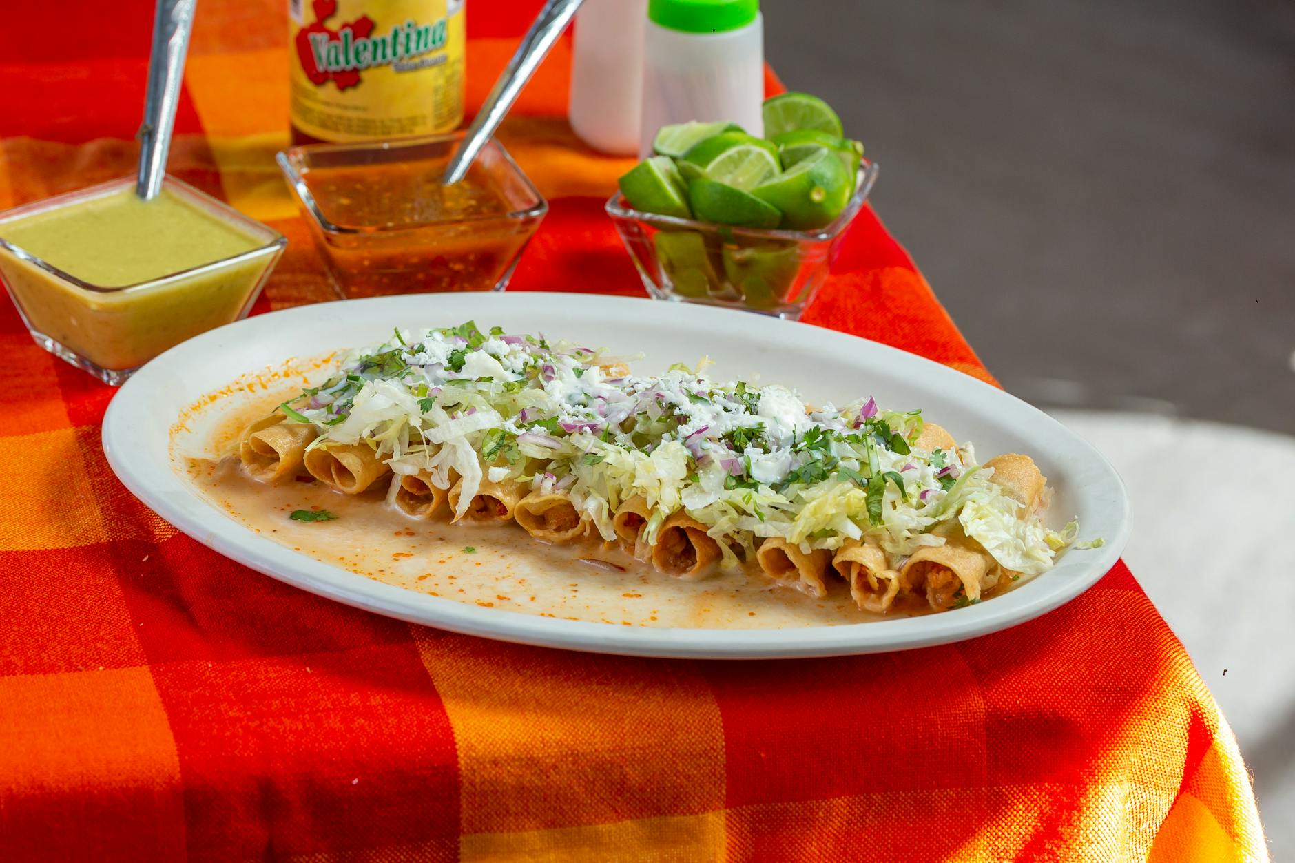 plate of mexican taquitos with dipping sauces
