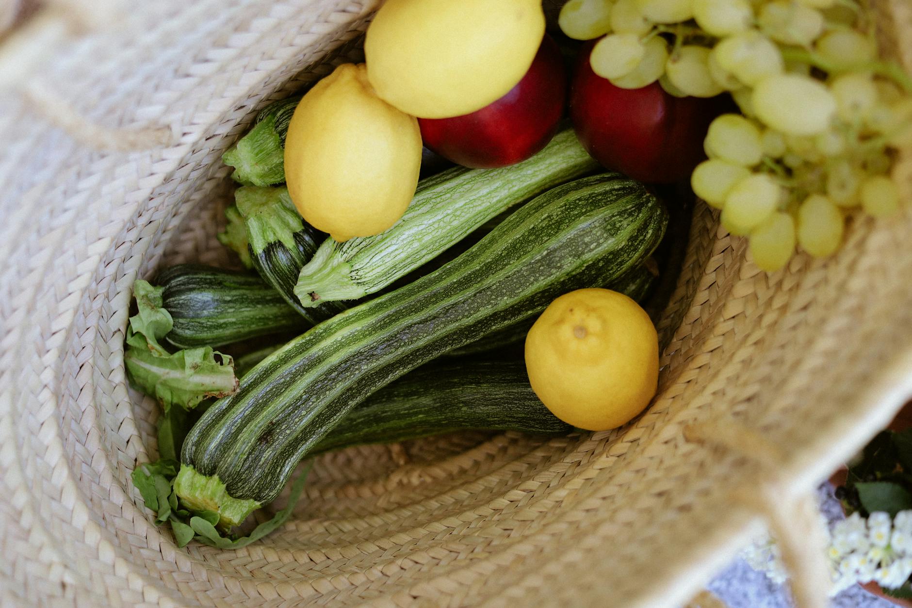 fresh produce in woven basket with zucchini and fruits