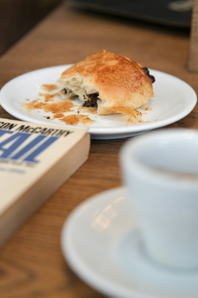 half eaten croissant with coffee and book