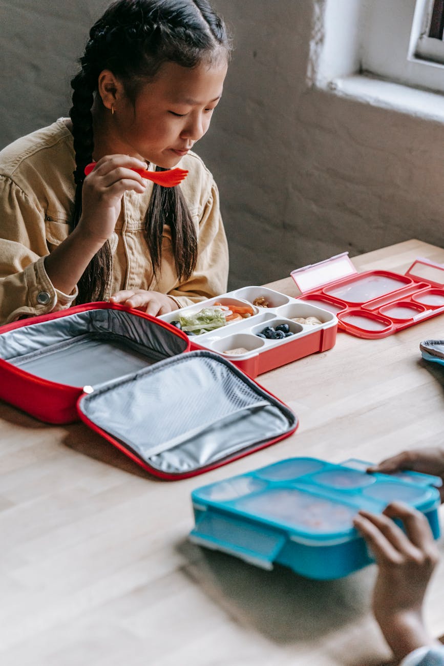 cute asian girl eating tasty organic meal in plastic container