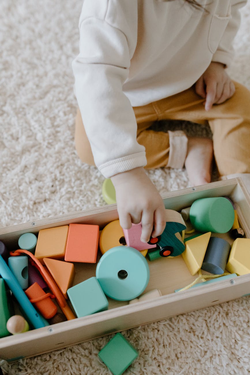 a kid playing the colorful wooden toys in the box